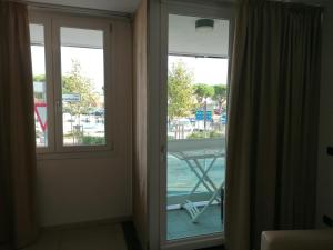 eine Tür zu einem Balkon mit Poolblick in der Unterkunft Residence Aprilia in Grado