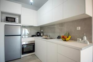 a kitchen with white cabinets and a bowl of fruit on the counter at Elounda Sunshine Place in Elounda