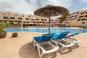 un grupo de sillas y una sombrilla junto a la piscina en Bonito Apto Mirador de la Gomera By Paramount Holidays, en Callao Salvaje