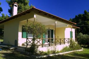 a small white house with a porch at Pine Tree Cottage in Nea Skioni