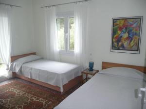 a bedroom with two beds and a window at Pine Tree Cottage in Nea Skioni