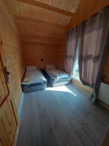 twee bedden in een houten kamer met een raam bij Haus Zielony und Haus Czerwony 