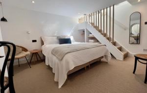 a white bedroom with a bed and a staircase at Rosa - Joss Bay in Kent