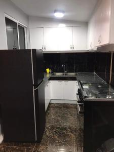 a kitchen with white cabinets and a black refrigerator at Catrionna Doll House in Tagum