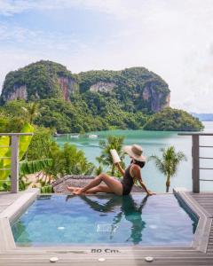 une femme assise dans une piscine avec un livre dans l'établissement Paradise KohYao, à Ko Yao Noi