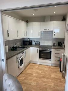 a kitchen with white cabinets and a washer and dryer at A glimpse of the championship in Carnoustie