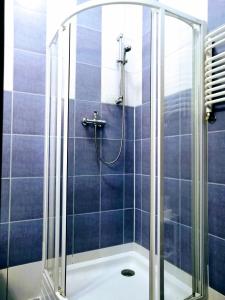 y baño con ducha de azulejos azules. en Szczecińskie Centrum Tenisowe en Szczecin