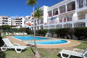 een resort met een zwembad en 2 stoelen en een palmboom bij Apartamentos King's in Quarteira