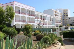 a white apartment building with a lot of plants at Apartamentos King's in Quarteira