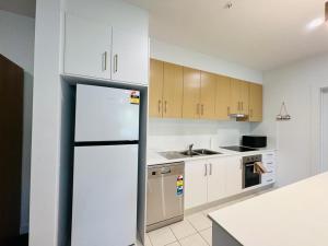 a kitchen with a white refrigerator and wooden cabinets at Lightsview Entire Apt 9 KM from CBD in Broadview