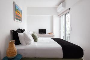 a bedroom with a bed with white walls and a window at Glyfada Unique Residence in Athens