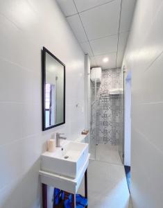 een witte badkamer met een wastafel en een spiegel bij Văn Hoa Hotel in Ho Chi Minh-stad