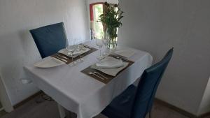 a white table with blue chairs and a table with wine glasses at Moderners Apartment am Hauptbahnhof in Minden in Minden