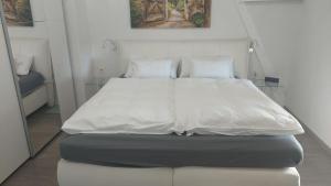 a bed with white sheets and pillows in a room at Moderners Apartment am Hauptbahnhof in Minden in Minden