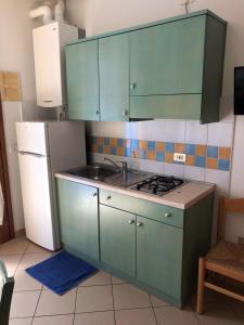a kitchen with green cabinets and a sink and a refrigerator at Enjoy your stay in our nice flat with pool in Rosapineta