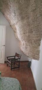 una habitación con una silla sentada bajo un techo en Casa Bajo la Roca, en Setenil