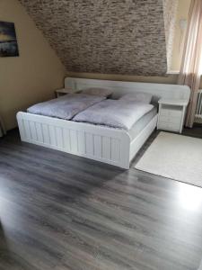 1 dormitorio con cama blanca y suelo de madera en Ferienwohnung Bergwiese, en Schwarzenbach am Wald