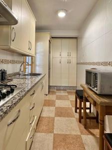a kitchen with white cabinets and a table with a microwave at Coqueto apartamento estación in Córdoba