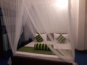 a bedroom with a canopy bed with green and white pillows at Udessa Rest Ella in Ella