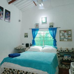 a bedroom with a bed with a blue blanket and a window at Casa Margarita in Santa Marta