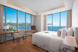 um quarto de hotel com uma cama e uma secretária com vista em A La Carte Da Nang Beach em Da Nang