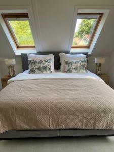 una camera da letto con un grande letto con due finestre di Villa June Rosy a Wijchen