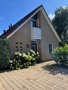 una casa di mattoni con un cespuglio di fiori di fronte di Villa June Rosy a Wijchen