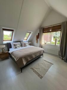 a white bedroom with a bed and two windows at Villa June Rosy in Wijchen