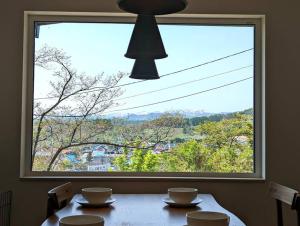a dining room table with a large window at Mountain View Totoro - spacious & sunny in Yoichi