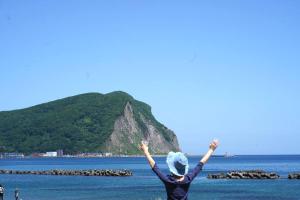 a woman with her arms in the air near the ocean at Mountain View Totoro - spacious & sunny in Yoichi