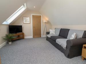 uma sala de estar com um sofá e uma televisão em Spicery Barn Loft em Exeter