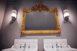 a bathroom with two sinks and a gold mirror at Ripple Cottage in Ripple