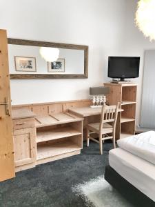 a room with a desk and a tv and a table at Wildauers Haidenhof STAY & SLEEP in Lienz