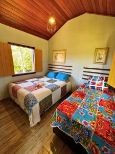 1 dormitorio con 2 camas y ventana en Sitio Recanto Maçussa, en Ouro Preto