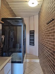 a bathroom with a shower and a brick wall at WILLA VASCO ADMIRAŁ in Rewa