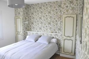 a bedroom with a bed with white sheets and floral wallpaper at Ô Rivage, maison familiale bord de Loire in Montjean-sur-Loire