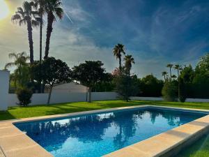 a swimming pool in a yard with palm trees at Villa con piscina, jardín y aire acondicionado en La Eliana-L'Eliana in Valencia