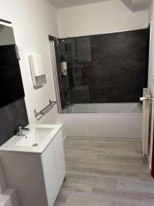 La salle de bains est pourvue d'une baignoire blanche, d'un lavabo et d'une baignoire. dans l'établissement Hôtel Les Jardins Dunkerque centre, à Dunkerque