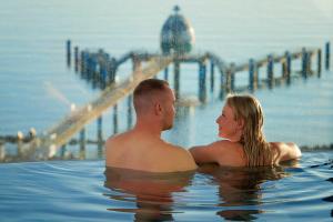 ein Mann und eine Frau sitzen in einem Swimmingpool in der Unterkunft FIRST Avalon in Ostseebad Sellin