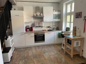 a kitchen with white cabinets and a wooden floor at Michaelishaus in Werder