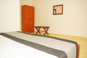 Owinro Beach Hotel & Restaurant - Waikkala في Kammala South: غرفة نوم بسرير وطاولة خشبية
