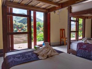 a bedroom with two beds and a large window at Dorm Riverside in Pakbeng