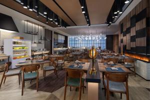 Four Points by Sheraton Shanghai Hongqiao في شانغهاي: مطعم بطاولات وكراسي خشبية وبار