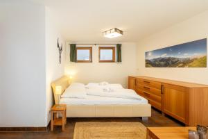 a bedroom with a white bed and a wooden dresser at Arch San Martin C in Scuol