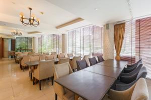 a dining room with tables and chairs and windows at Lantana Resort Hotel Bangkok in Bangkok