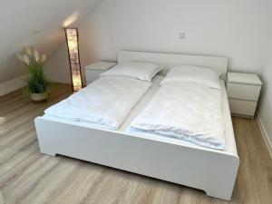 1 cama con sábanas blancas y almohadas en una habitación en Premium Apartment 75qm 3 Zimmer Küche, Balkon, Smart TV, WiFi, en Aalen