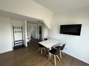 Habitación con mesa blanca, sillas y TV. en Premium Apartment 75qm 3 Zimmer Küche, Balkon, Smart TV, WiFi, en Aalen
