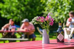 a bottle of wine and a vase of flowers on a table at Wye Glamping in Velindre