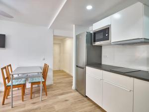 a kitchen with white cabinets and a table with chairs at NEW Plaza Elíptica Metro Bus 15 min centro 3d Luxe reformado in Madrid