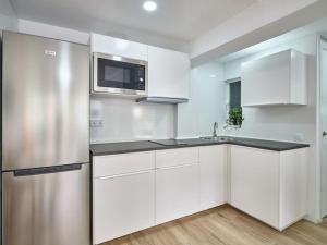 uma cozinha com armários brancos e um frigorífico de aço inoxidável em NEW Plaza Elíptica Metro Bus 15 min centro 3d Luxe reformado em Madri